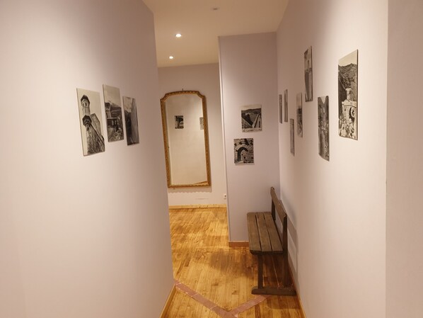 Un pasillo con piso de madera, un banco y fotografías blanco y negro en las paredes.