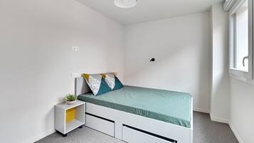 Een kleine, moderne slaapkamer met een enkel bed, een nachtkastje met een plant en een raam met uitzicht.