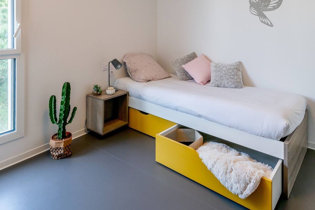 Une chambre à coucher moderne avec un lit, des tables de chevet, un cactus et une fenêtre.
