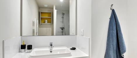 Un baño con un lavamanos blanco, un mueble de color amarillo y un espejo grande.
