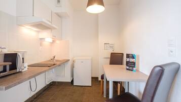 A compact kitchen with a microwave, refrigerator, and a dining area with a table and chairs.