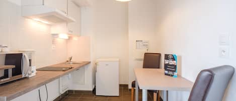 Una cocina compacta equipada con microondas y refrigerador, y un comedor con mesa y sillas.