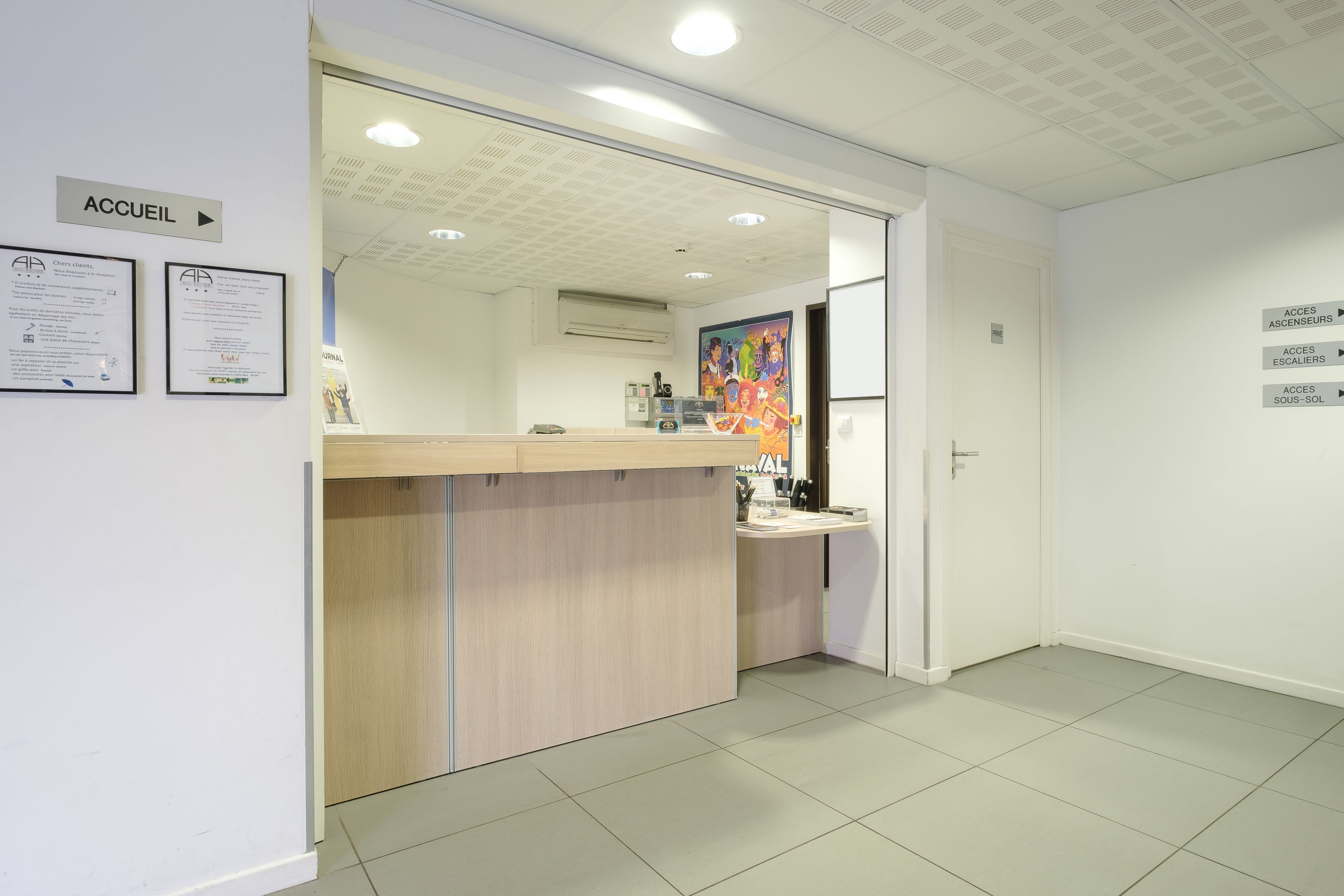 A reception area with a wooden counter, a door leading to a waiting area, and a wall with directional signs.