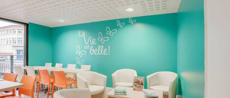 A modern interior with teal walls, white furniture, and a ceiling with a grid pattern.