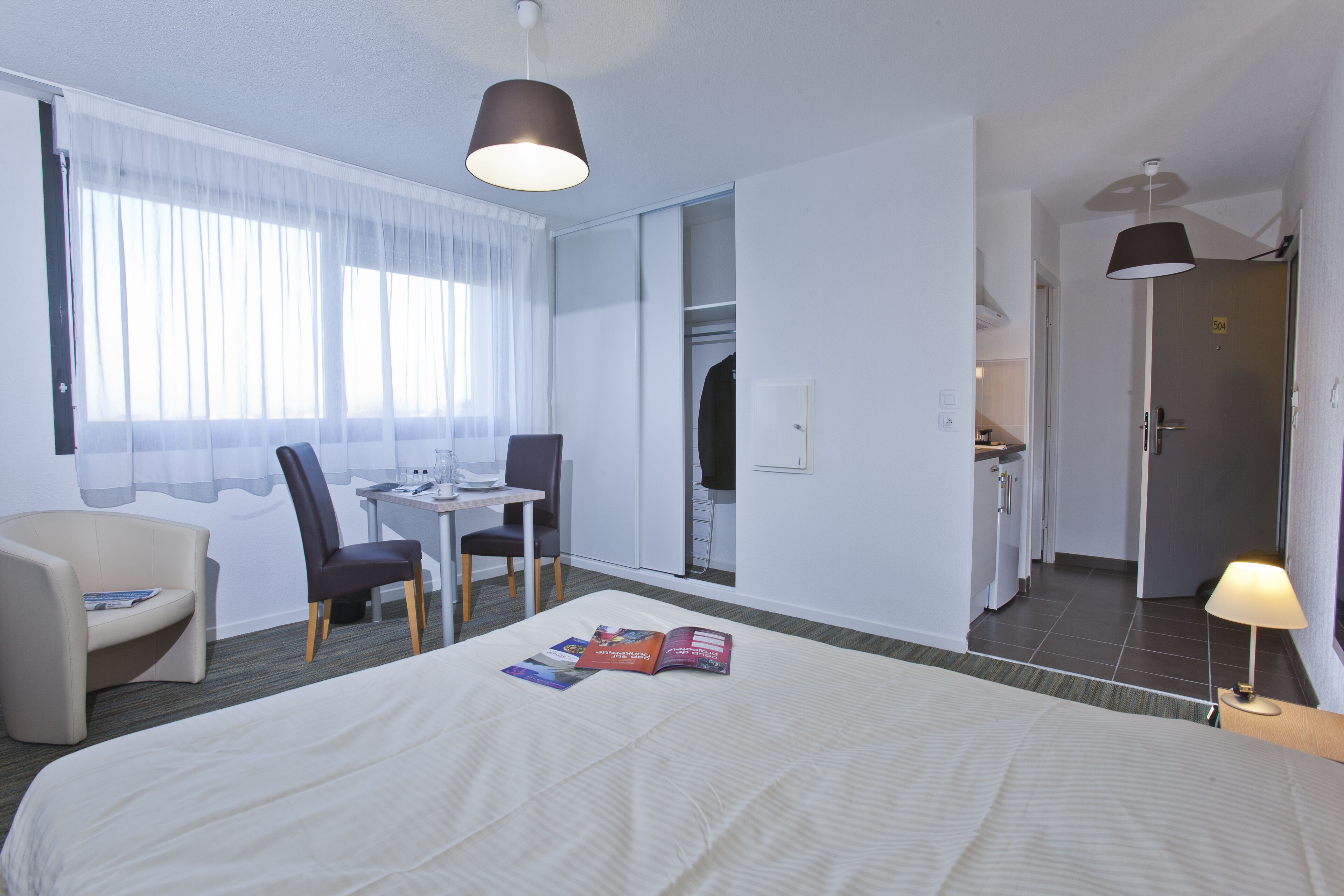 Une chambre d’hôtel comprenant un lit, un bureau, une chaise, une table et une armoire.