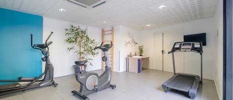 A fitness room with treadmills, an elliptical, and a wall-mounted TV.