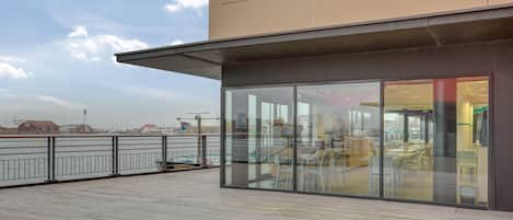 A modern building with large glass windows and a wooden deck.