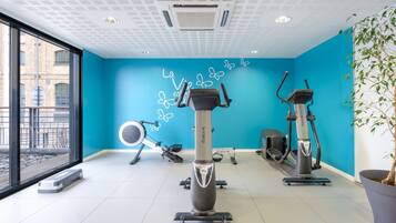 A gym with exercise equipment, a blue wall, and a large window.