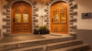 A hotel entrance with two ornate wooden doors, stone walls, and a sign indicating the hotel name. - Hotel Allalin Saas-Fee (Saas-Fee)