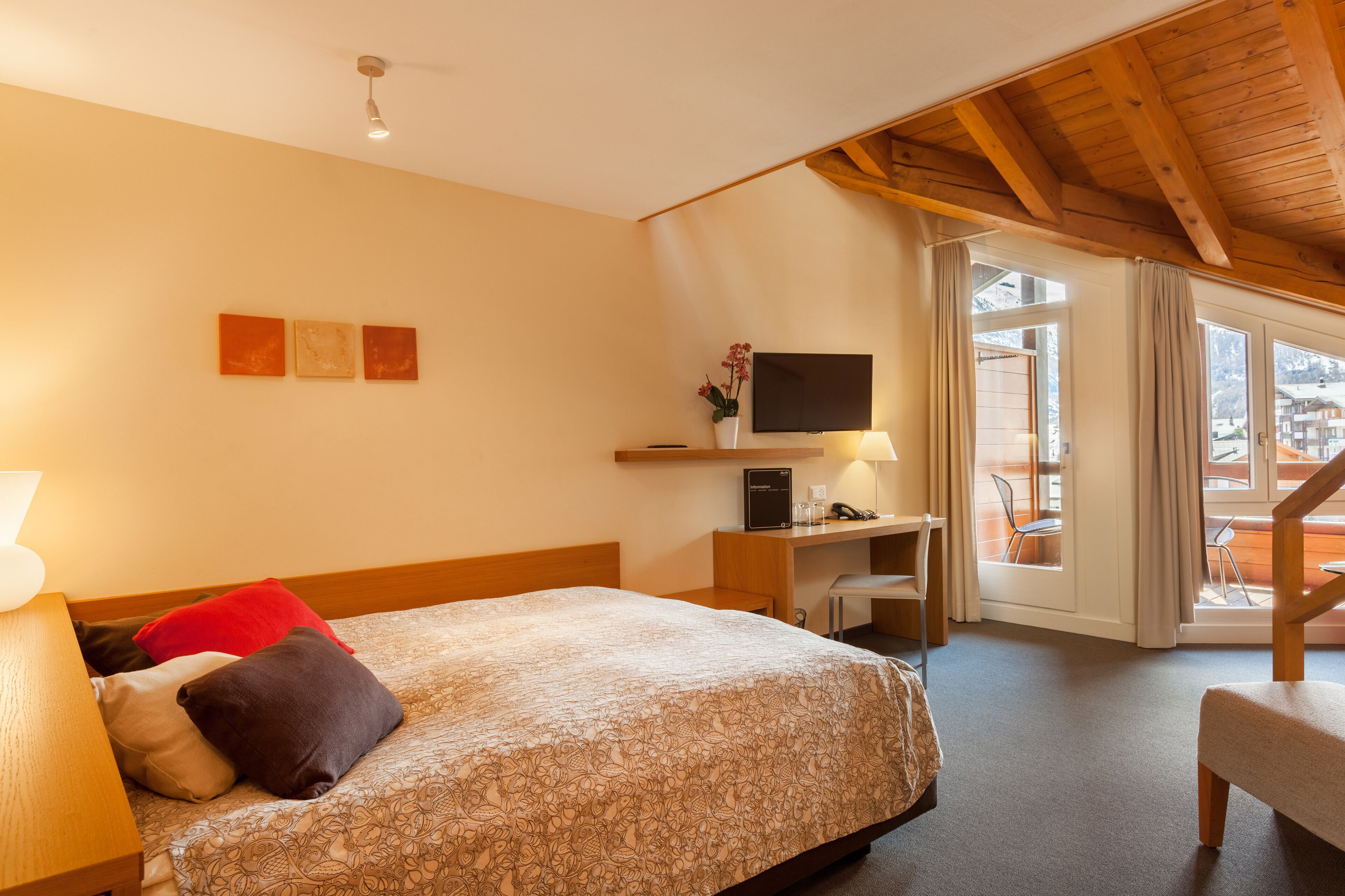 Una camera d'albergo con un letto, una scrivania, una sedia, una TV e ampie finestre.