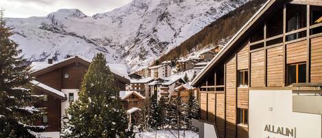 A snow-covered mountain resort with wooden buildings and a sign reading "ALLALIN."
