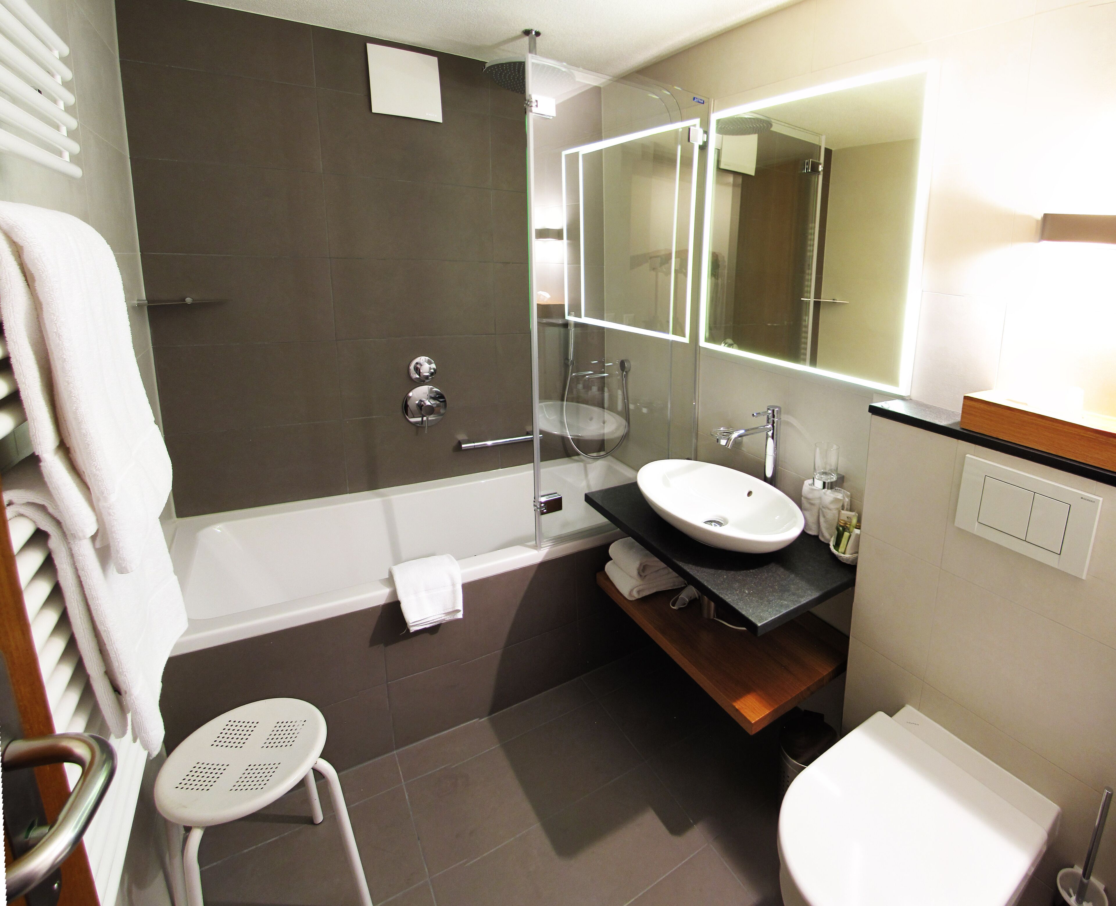 A modern bathroom with a glass-enclosed shower, a white sink, and a toilet.