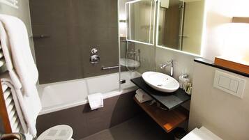 A modern bathroom with a glass-enclosed shower, a white sink, and a toilet.