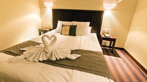 Una habitació d'hotel amb un llit ben fet, un capçal de llit, dues taules de nit amb làmpades i un quadre a la paret.