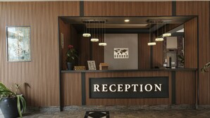 A reception area with a wooden panel wall, a 'RECEPTION' sign, hanging pendant lights, and a world map decoration. - Hotel Bella Bravo (Alanya)