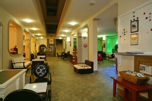 A hotel lobby with a reception desk, seating areas, and a staircase leading to other floors.