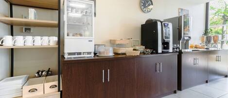 Una cocina moderna con cafetera, un reloj y una ventana con vistas a zonas verdes.