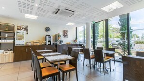 Un café moderne avec des tables et des chaises, une machine à café et une horloge au mur.