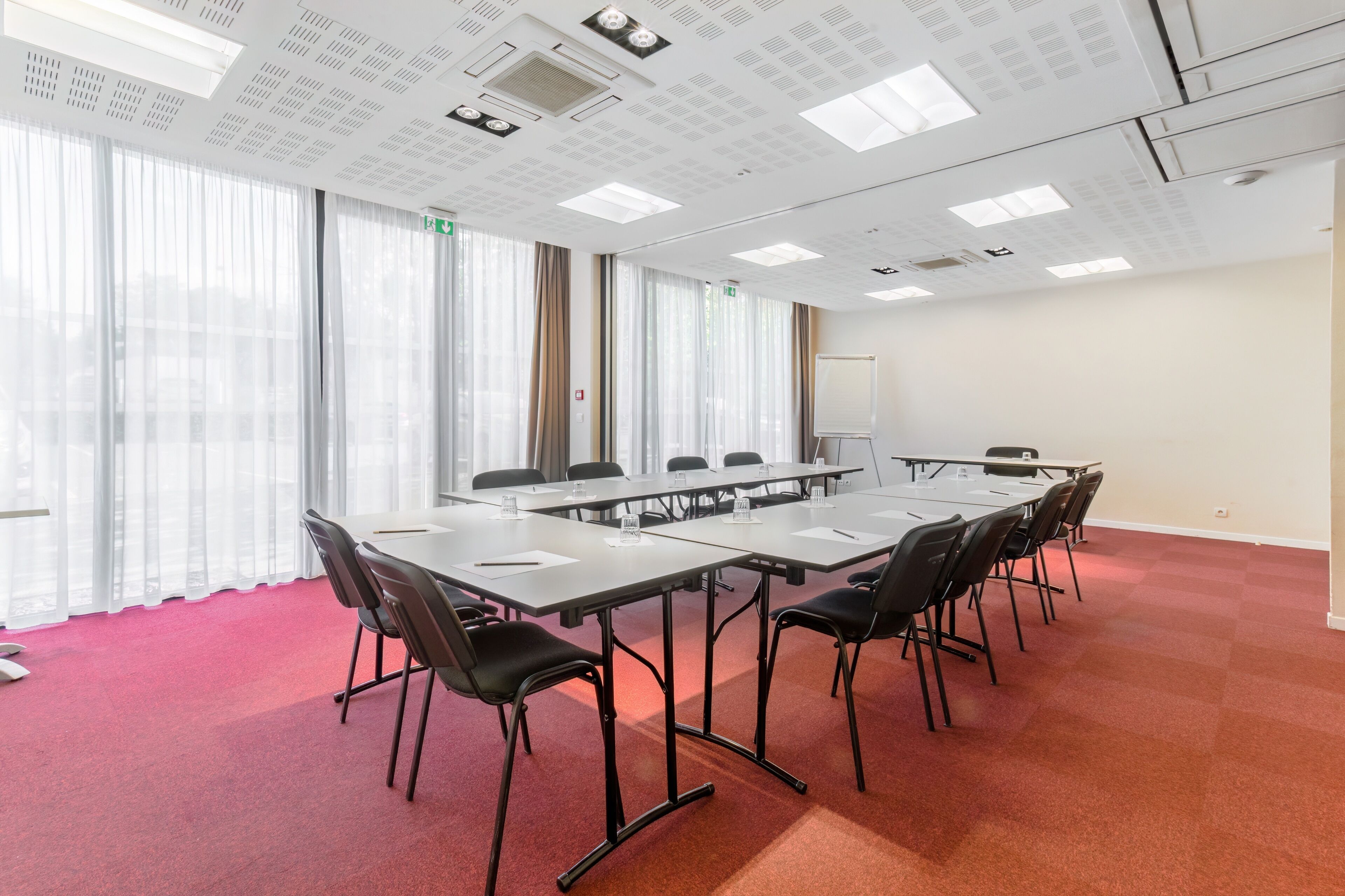 A conference room with a long table, black chairs, and a whiteboard.