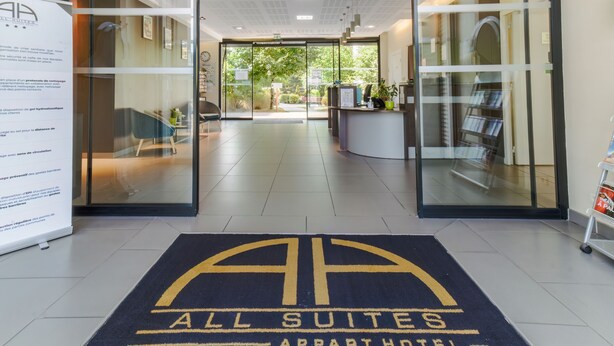 L’entrée d’un hôtel, avec un comptoir d’accueil, un espace d’attente et une vue sur l’extérieur.