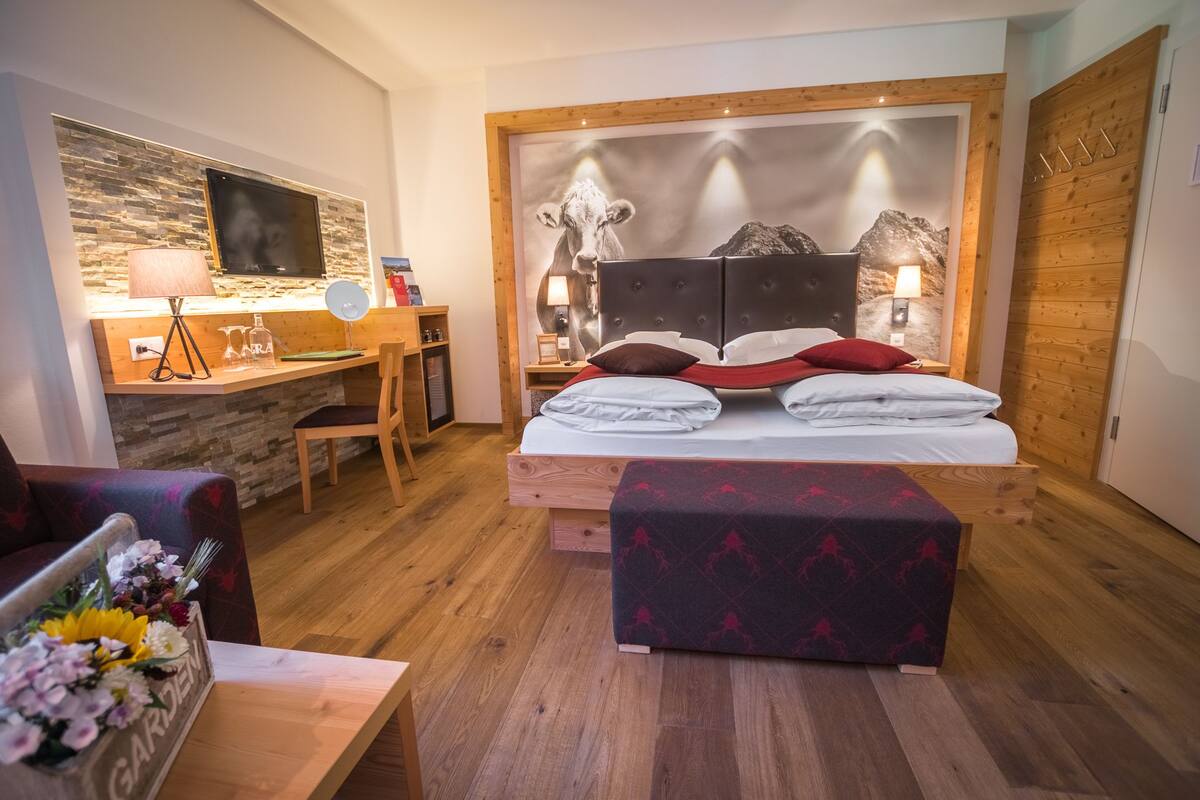 A bedroom with a bed, a desk, a chair, and a wooden floor.