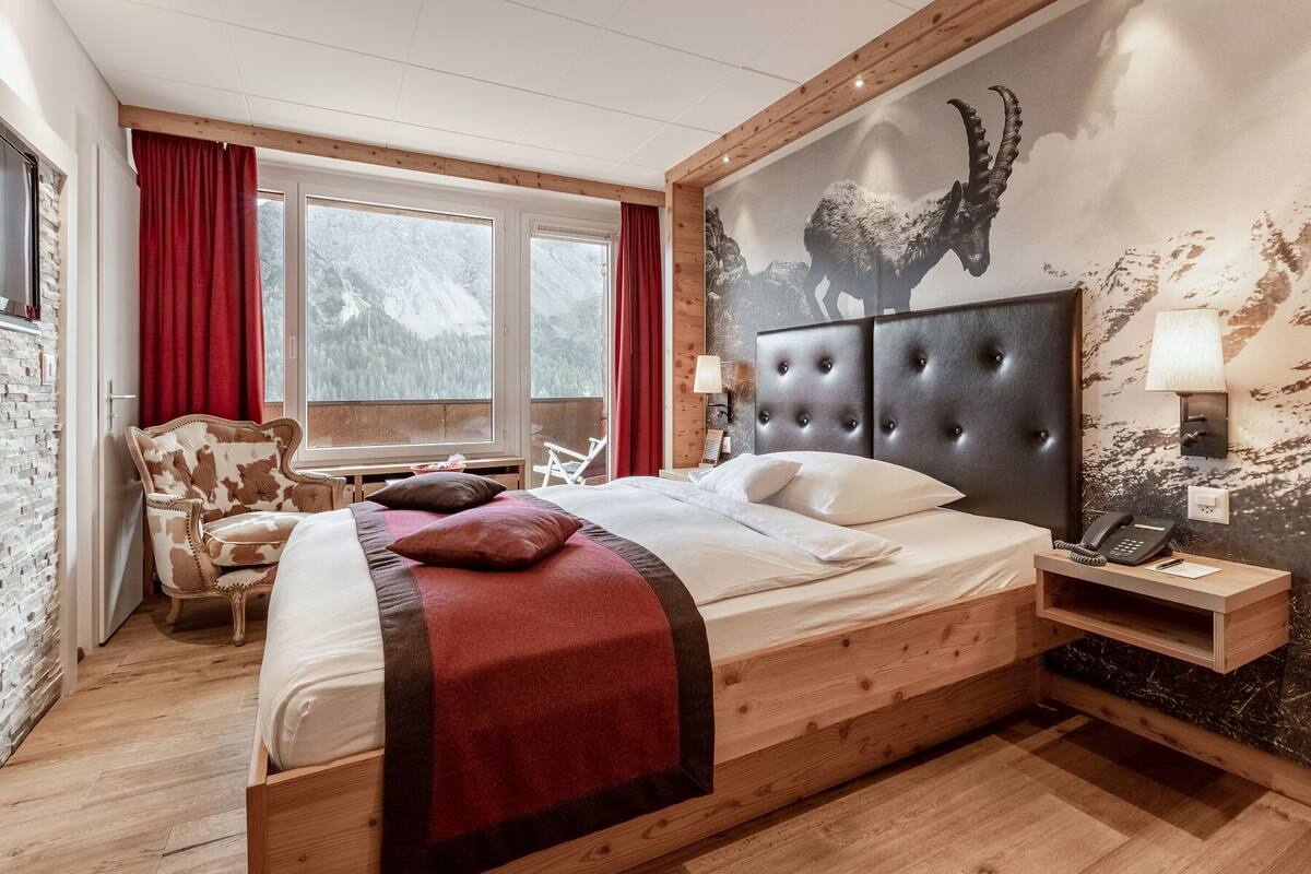 A bedroom with a large bed, a wooden headboard, a desk, and a chair.