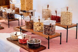 Un bufé con distintos alimentos en recipientes de vidrio sobre bandejas de madera.