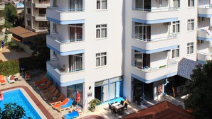 Un hôtel à plusieurs étages doté de balcons, d’une piscine et d’un espace extérieur aménagé pour s’asseoir.
