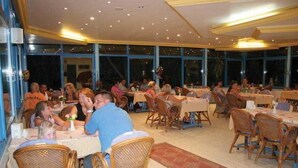 Un restaurant doté de nombreuses tables et chaises, de grandes fenêtres et d’un sol carrelé.