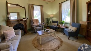 A cozy living room with a fireplace, comfortable seating, and a large mirror. - Hanlon Guest House (Stanley)