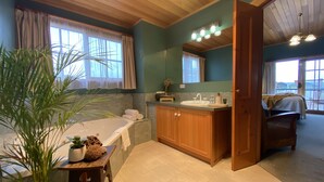 A bathroom with a bathtub, sink, and wooden cabinets. - Hanlon Guest House (Stanley)