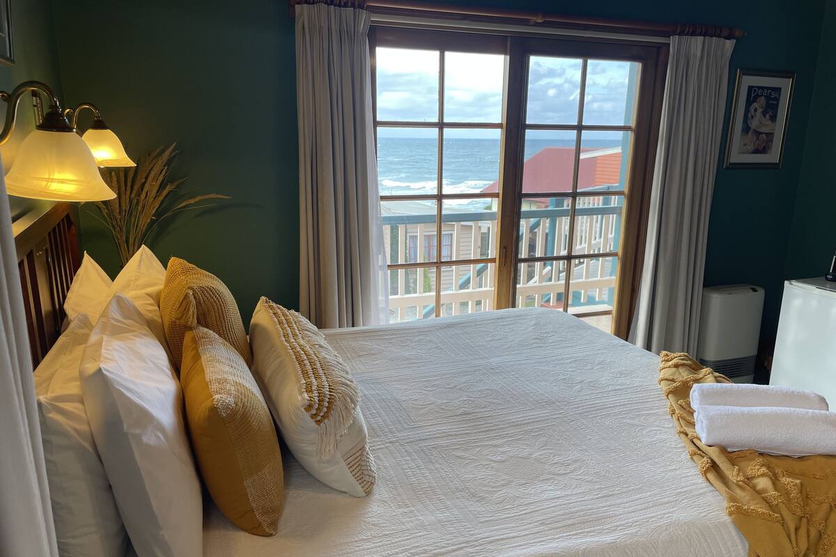 A hotel room with a large bed, a view of the ocean, and a balcony.