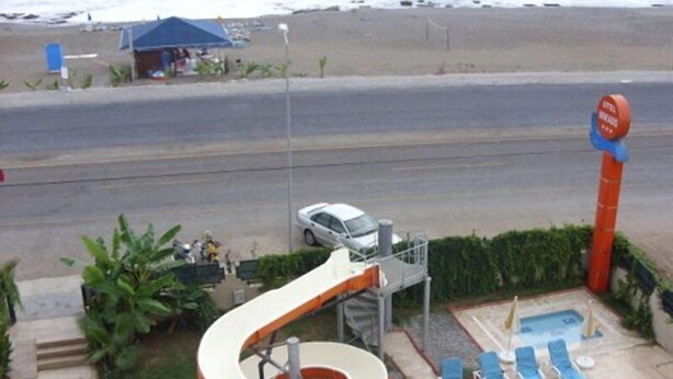 A beachside pool area with a water slide, lounge chairs, and a lifeguard stand. - Mikado Hotel (Alanya)