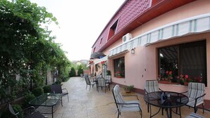 Eine Terrasse mit Sitzgelegenheiten im Freien und ein Gebäude mit rotem Dach und rosa Wänden.