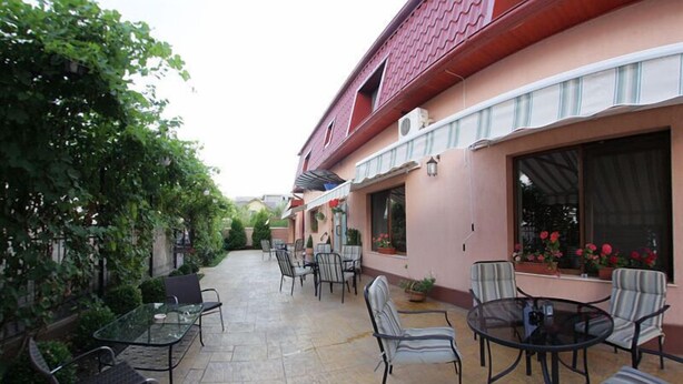 En terrasse med udendørs møbler og en bygning med rødt tag og pink vægge.