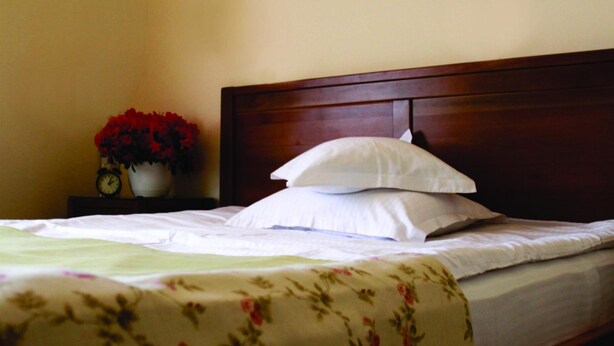 Ein ordentlich bezogenes Bett mit weißer Bettwäsche und einer Bettdecke mit Blumenmuster.