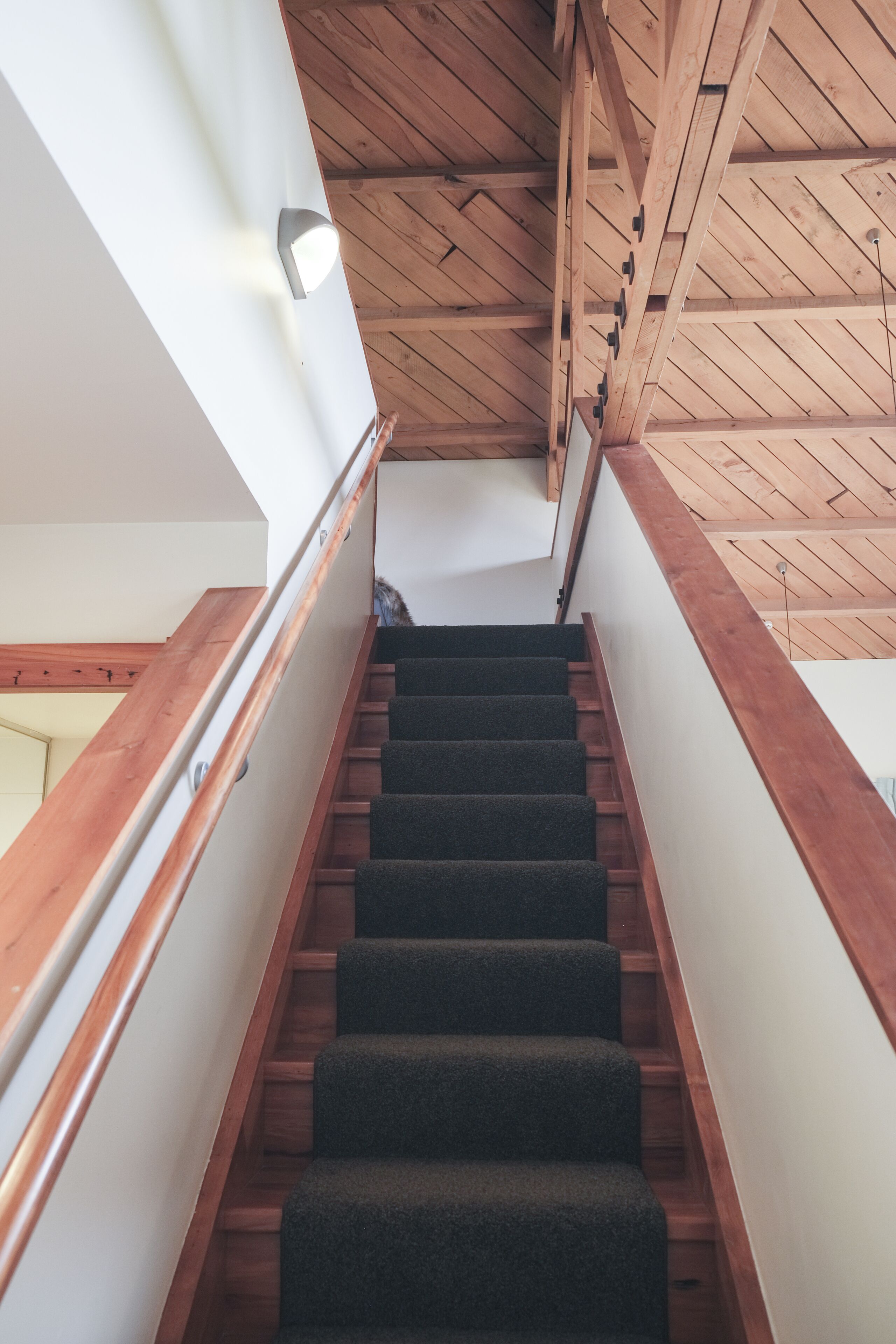 A staircase with wooden railings and carpeted steps leading to a higher floor.