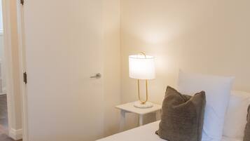 A hotel room with a bed, a bedside lamp, and a door.