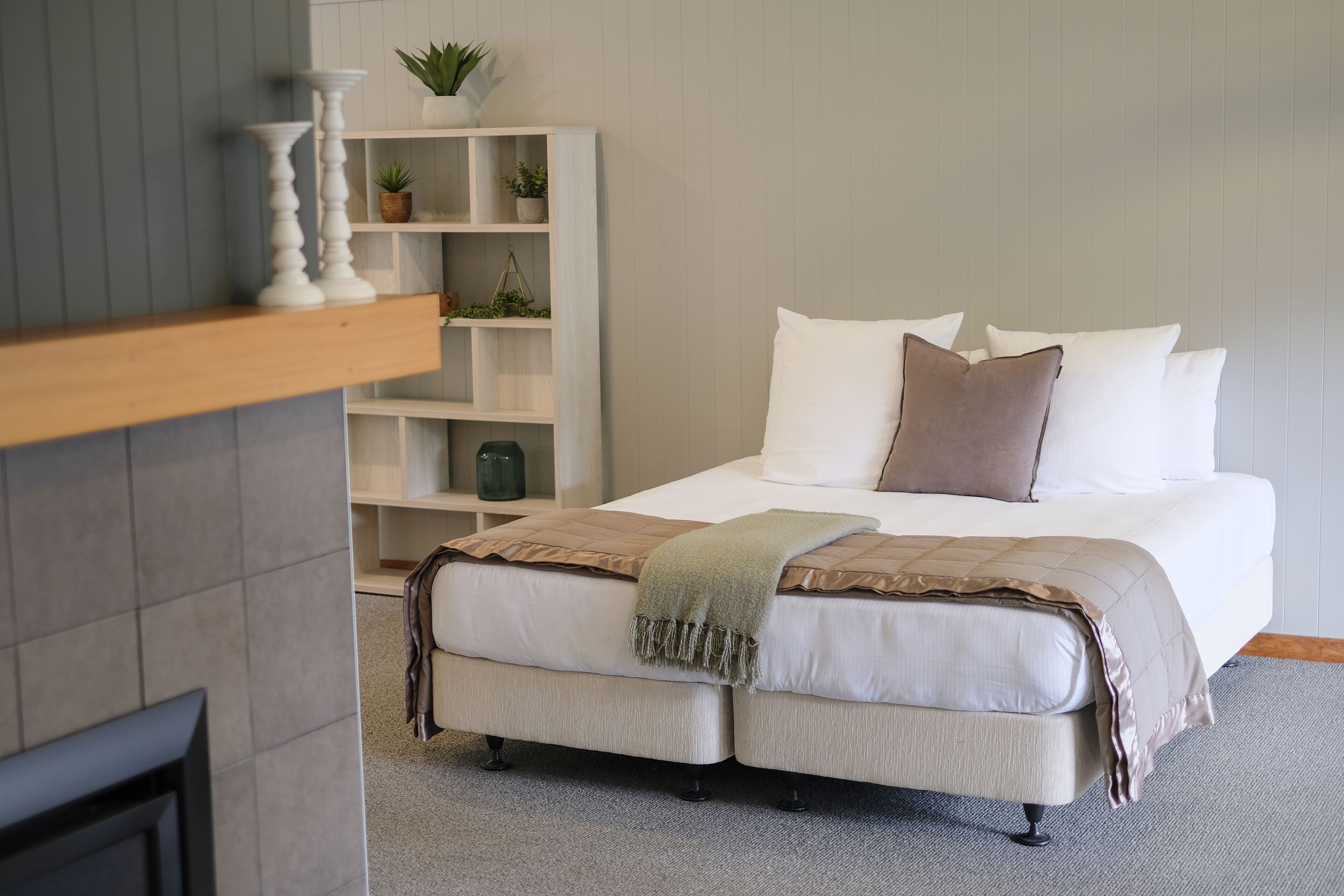 A bedroom with a bed, bedside tables, a bookshelf, and a fireplace.
