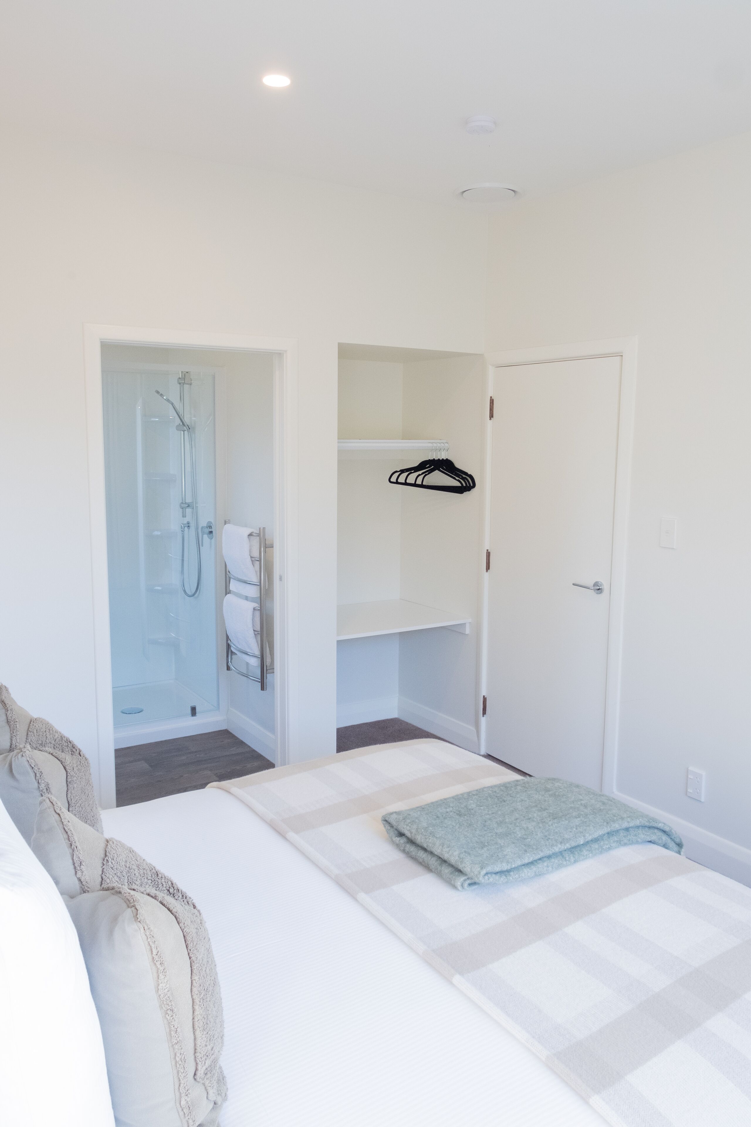 A bedroom with a bed, a walk-in closet, and a shower area.
