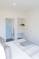 A bedroom with a bed, a walk-in closet, and a shower area.