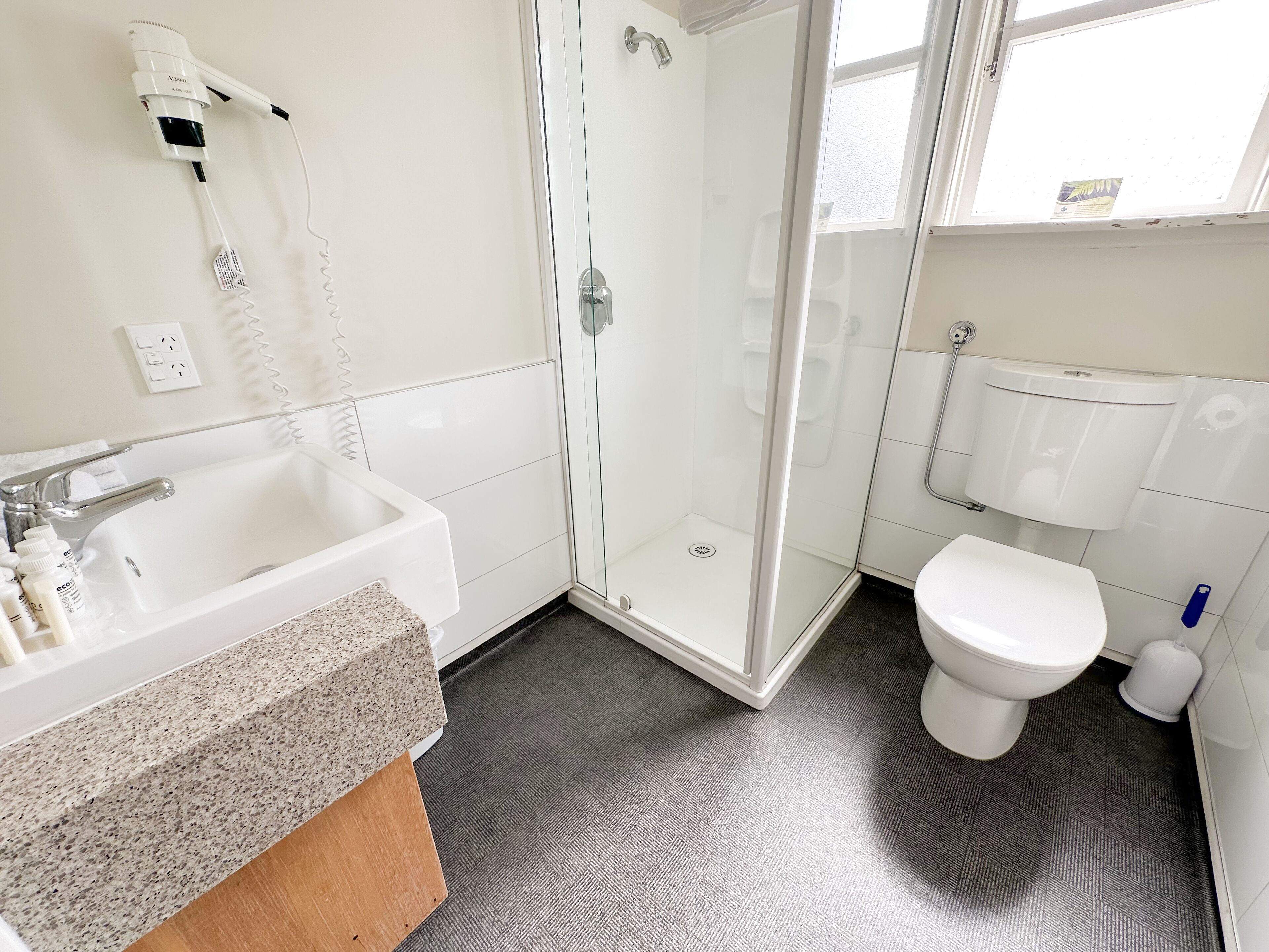 Une salle de bain avec un lavabo blanc, une cabine de douche en verre et des toilettes.