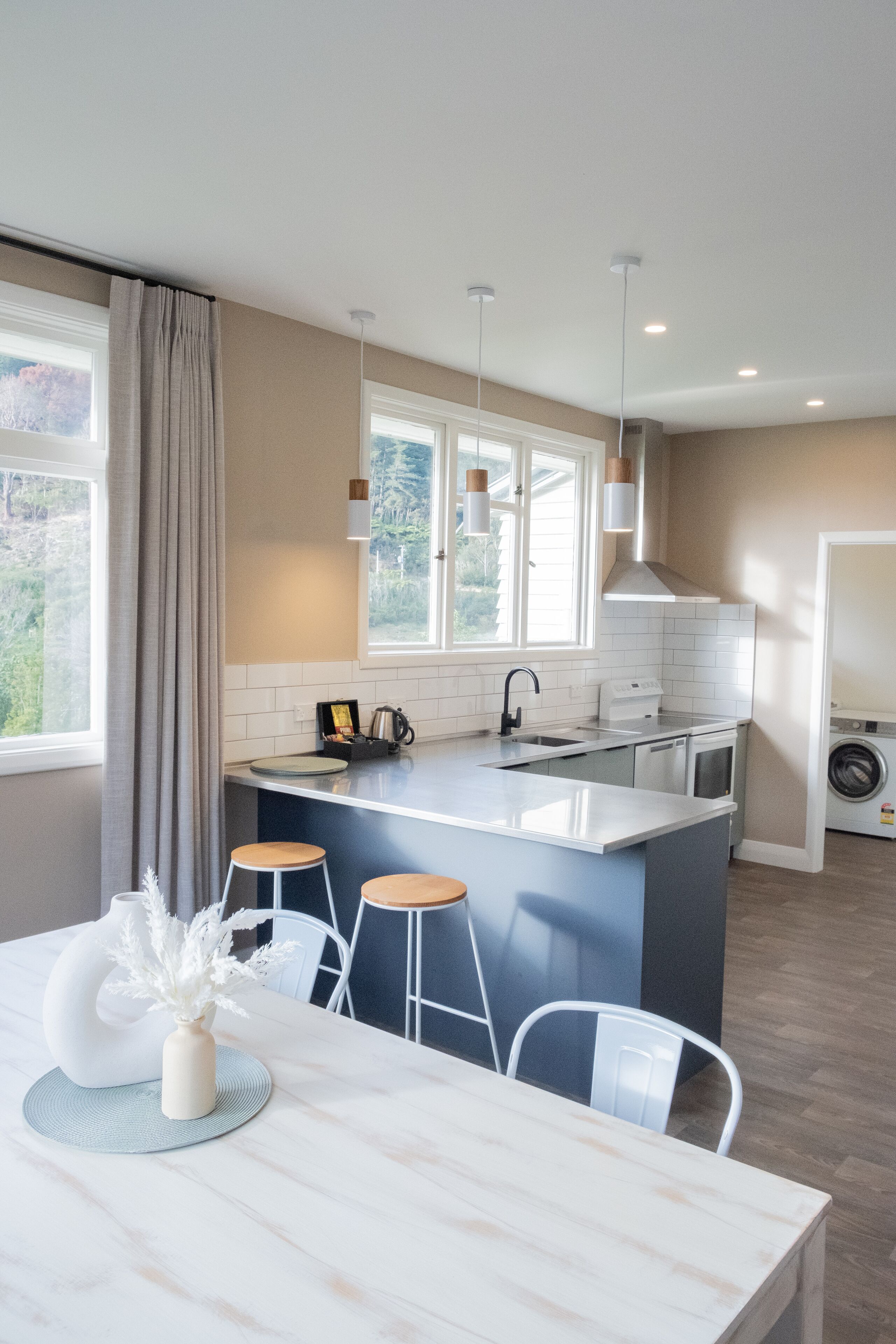 A modern kitchen with a central island, white cabinetry, and a built-in dishwasher.
