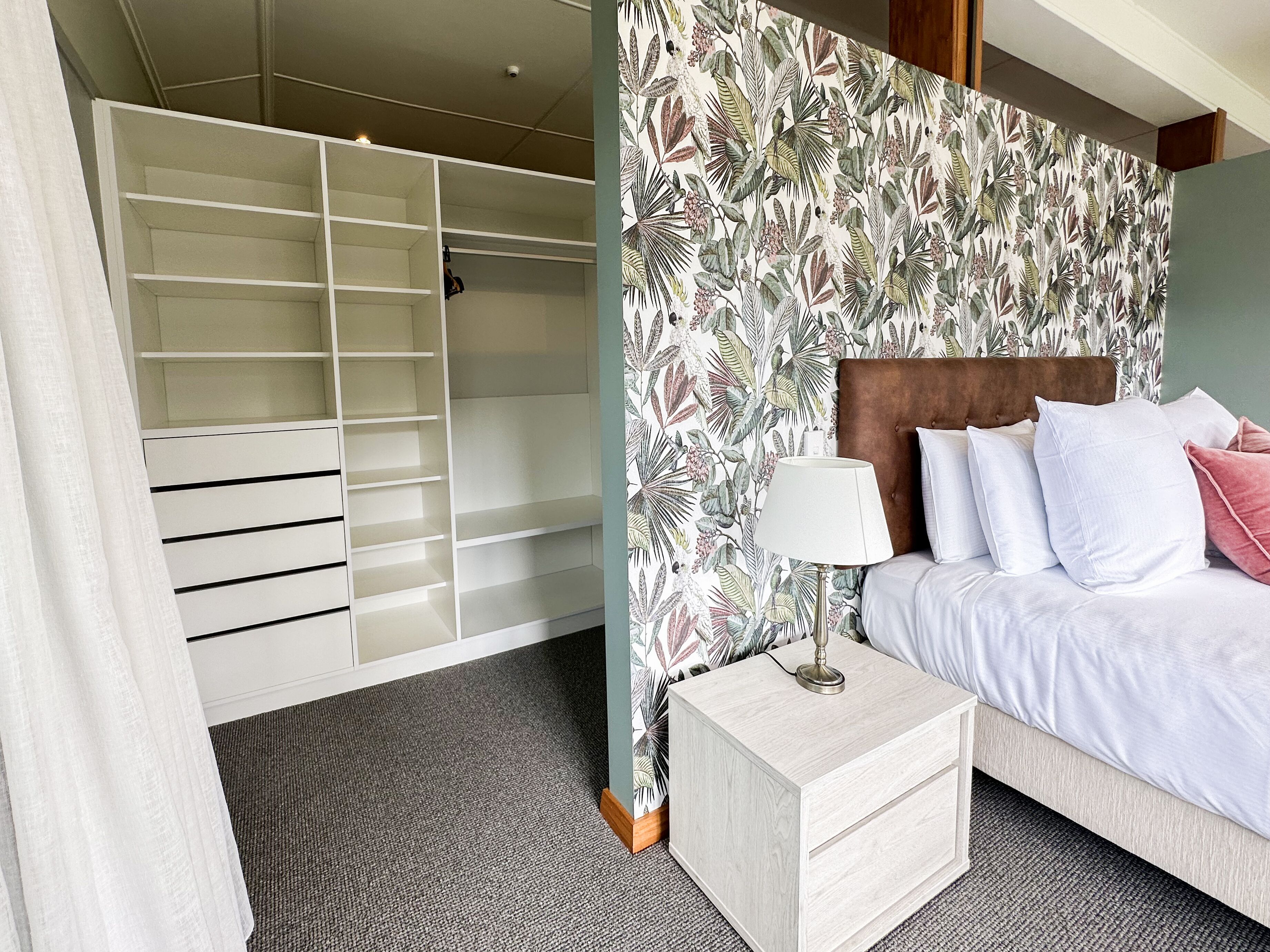 A bedroom with a bed, bedside table, and a wardrobe.