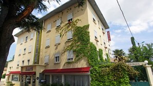 Un hotel con fachada color beige, toldos rojos y un letrero que dice "HOTEL GEORGES".