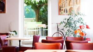 Interior de un restaurante con sillas de cuero rojo, mesas blancas y vistas al exterior.