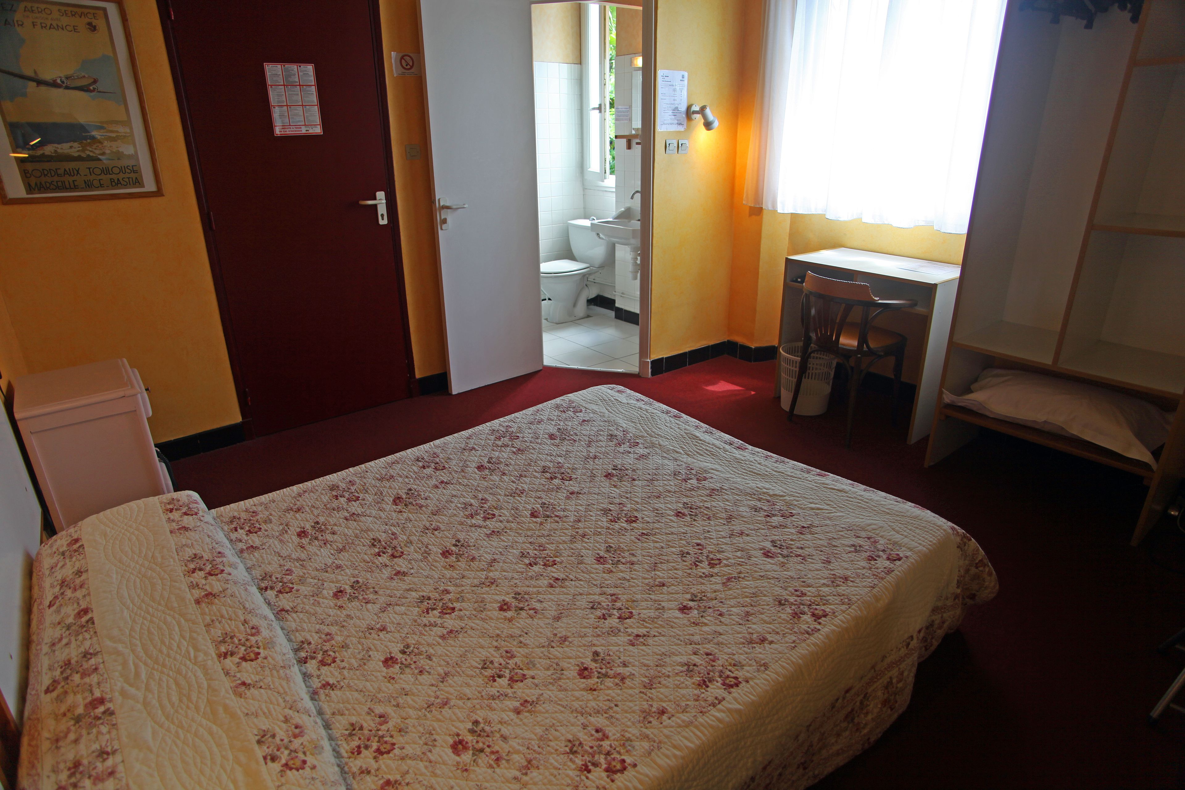 Ein Schlafzimmer mit Bett, Schreibtisch und angrenzendem Badezimmer.