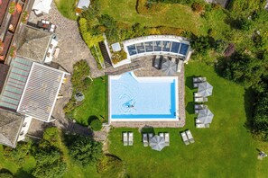 Vista aérea de una propiedad con piscina, mobiliario exterior y terraza cubierta.