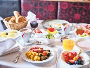 Un desayuno con diferentes platos, utensilios y una cesta de pan.