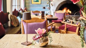 Un interior acogedor con chimenea, muebles de madera y un florero con flores.